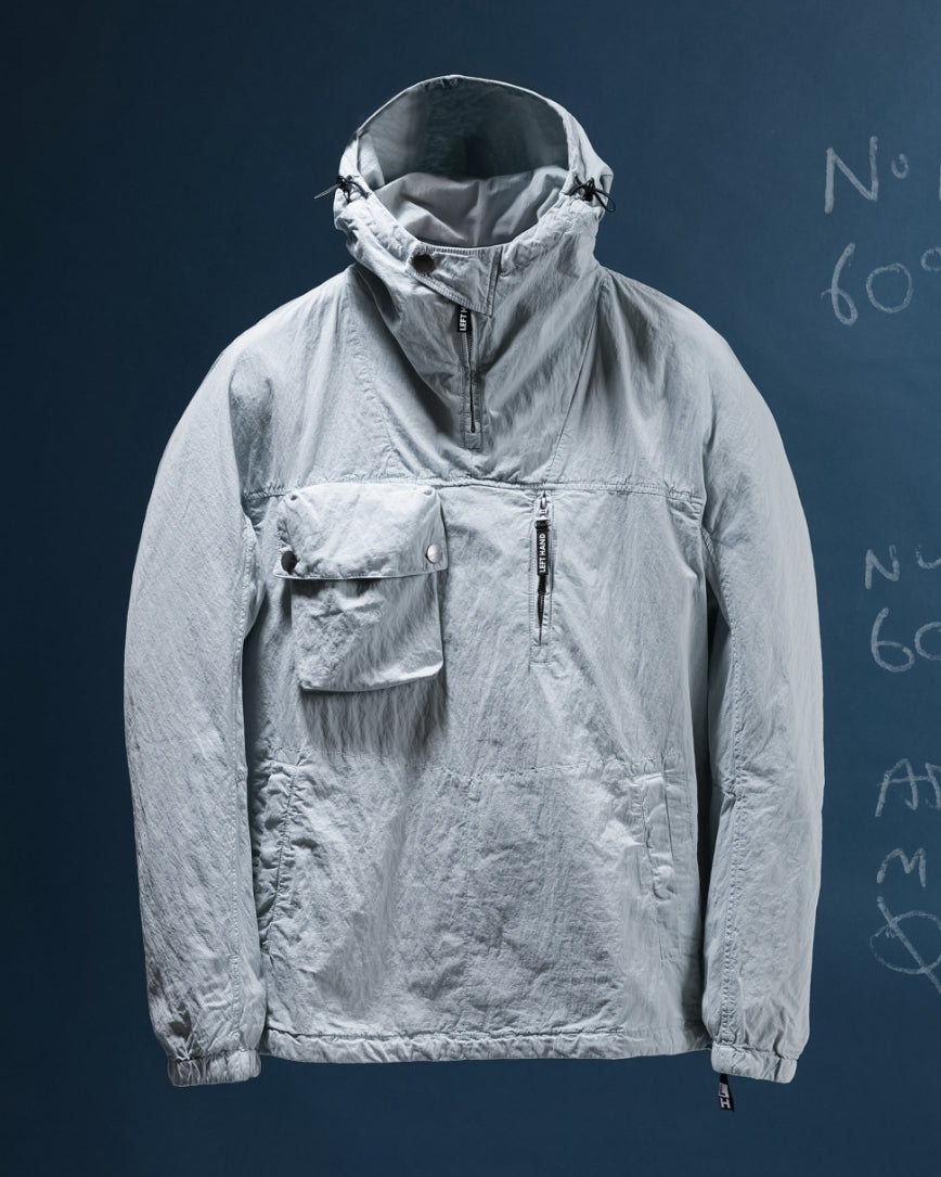 Light gray Left Hand Adda Smock jacket with a hood on a dark blue background.