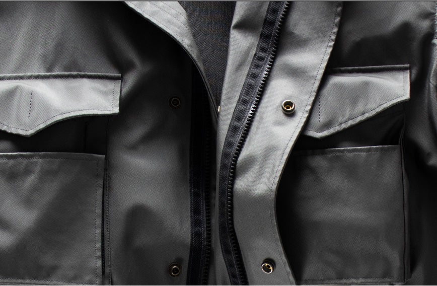 Closeup of Left Hand Thermojoint Jacket: gray fabric with flap pockets, black zipper, and metallic buttons on detailed design