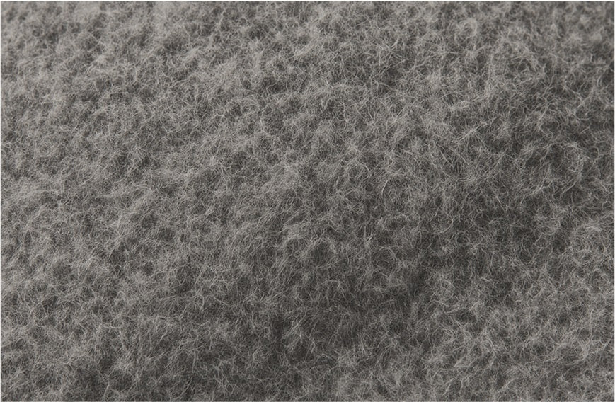 Closeup of Massimo Osti's Rubberwool fabric: gray wool coated with rubber, showing textured, breathable surface for waterproof vintage sportswear.