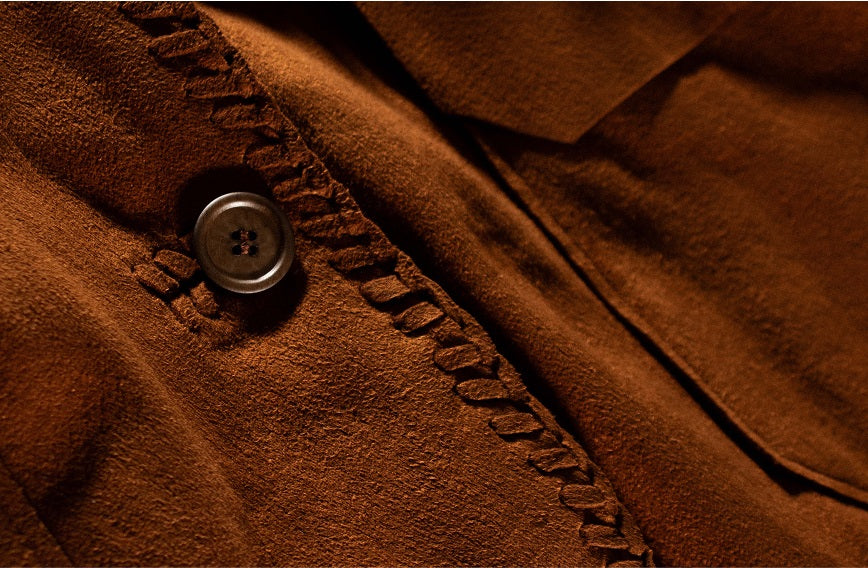 Closeup of Left Hand Micro fabric: brown textured material with pressed fibres, featuring a button and decorative stitching.