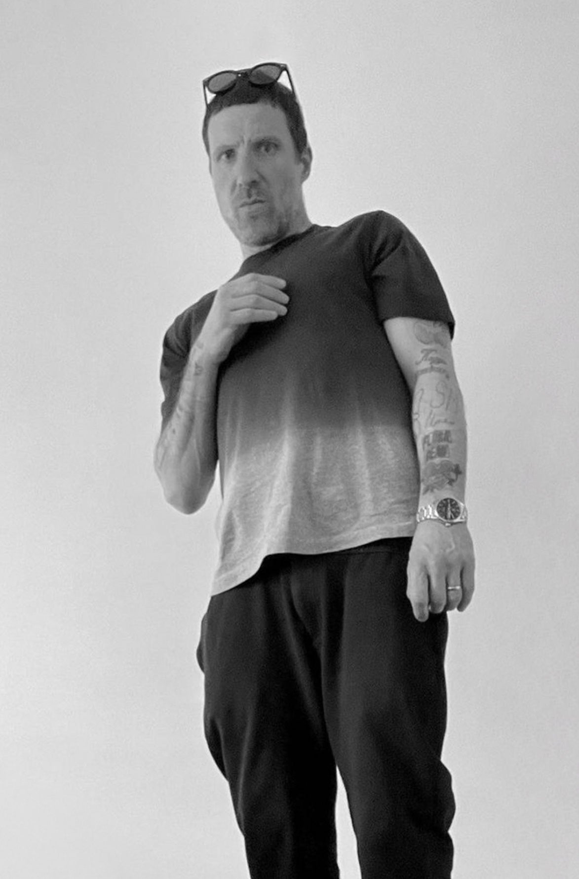 Jason Williamson, frontman of Sleaford Mods, in a black and white portrait wearing casual clothing and sunglasses on his head.