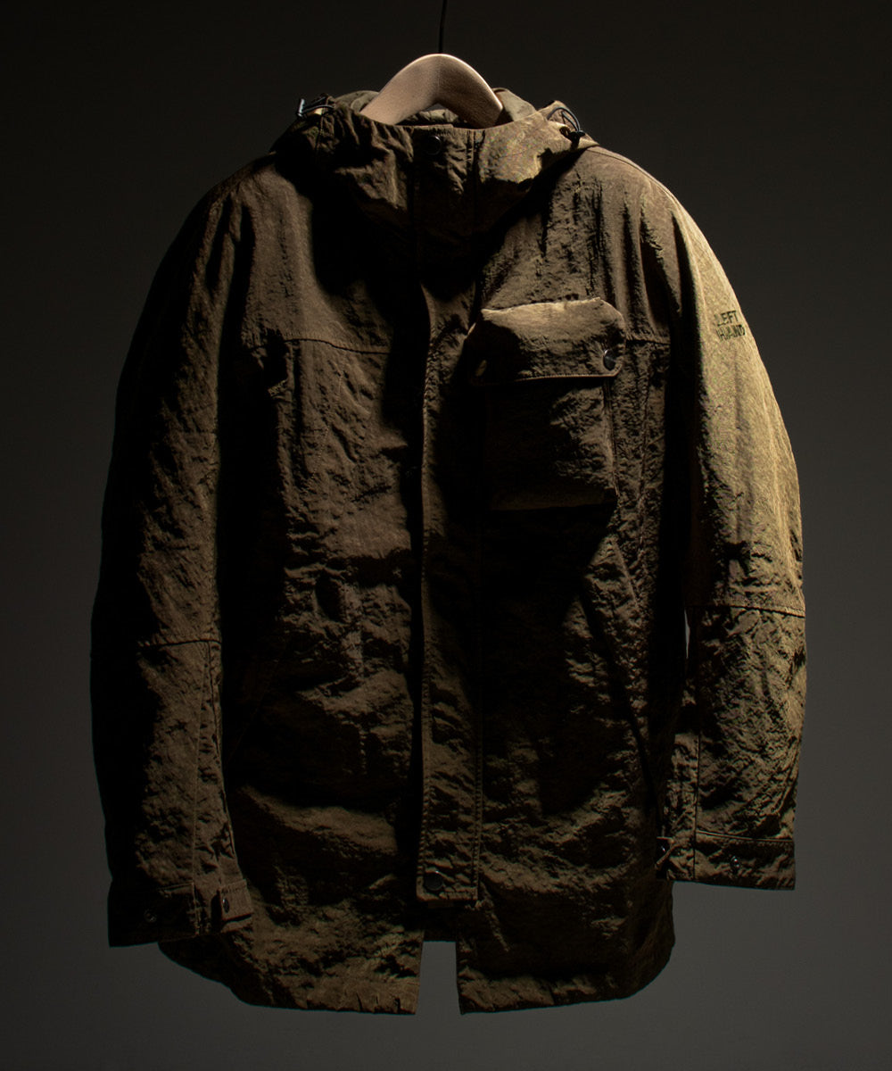 Left Hand Enna Parka Jacket in dark olive with hood, chest pocket and textured finish, displayed against a dark background.