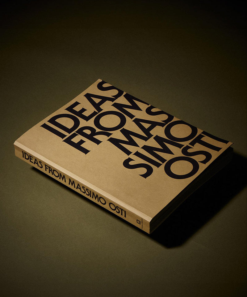Book titled "Ideas From Massimo Osti" with bold black lettering on a brown cover, displayed on a dark surface.