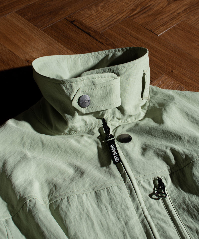 Left Hand Lys Blouson jacket in light green with high collar, zip fastening and snap button detail.